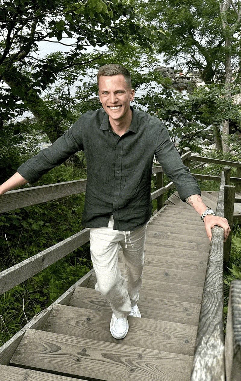 Oliver leaning on a railing in a green garden
